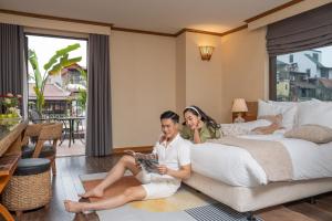 een man en vrouw op een bed in een hotelkamer bij MK Premier Boutique Hotel in Hanoi