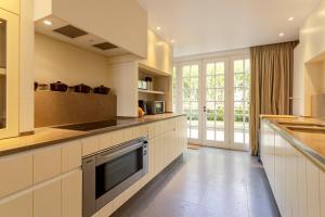 a large kitchen with white cabinets and a large window at Villa Pauline in De Panne