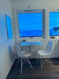Habitación con 2 sillas, mesa y 2 ventanas en Holiday home with sauna in the Arctic Caribbean, Tromsø, en Tromsø