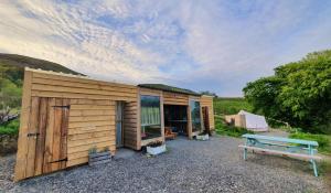 un pequeño cobertizo de madera con un banco al lado en Calon Y Goedwig Glamping, en Llandovery