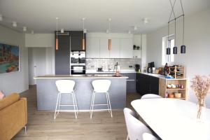 una cocina con armarios blancos y taburetes blancos en Peaceful Modern 2 BR Penthouse with nice view, en Hesperange