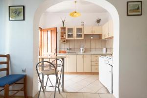 uma cozinha com armários brancos e uma mesa e cadeiras em Studio Apartman Ema 2 em Gornji Karin