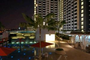 八打靈再也的住宿－Eve Suite 2 bedrooms At Ara Damansara，享有棕榈树和遮阳伞的建筑的夜景