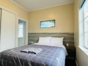 a bedroom with a bed with a blue blanket at Amber Hill A in Pukekohe East