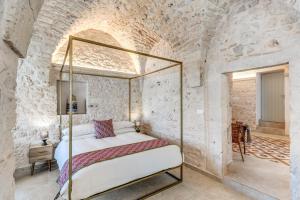 1 dormitorio con 1 cama en una pared de piedra en Il Violino e Il Sassofono, en Ceglie Messapica