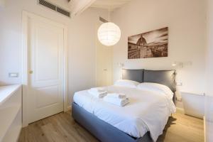 a bedroom with a large white bed and a pendant light at Santa Croce Top by Mmega in Florence
