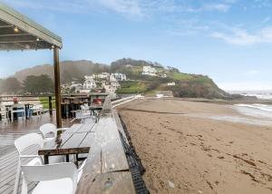 a beach with tables and white chairs and the ocean at Millendreath Beach Resort in Looe