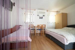 een slaapkamer met een bed en een tafel en stoelen bij Studio Apartman Ema in Gornji Karin