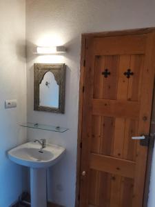 a bathroom with a sink and a wooden door at Ksar Montana Gîtes, Chambres piscine in Taforhalt