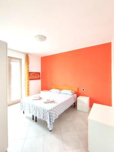 1 dormitorio con cama y pared de color naranja en Appartamenti Costa dei Trulli en Torre Canne