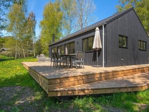 ein schwarzes Haus mit einer Holzterrasse mit einem Tisch und Stühlen in der Unterkunft Holiday home Ebeltoft CLXXXIX in Ebeltoft