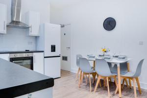y cocina con mesa, sillas y nevera. en Spacious 4 Bedroom house near Leeds CC, en Beeston Hill
