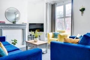 Spacious 4 Bedroom house near Leeds CC في Beeston Hill: غرفة معيشة مع كراسي زرقاء ومرآة