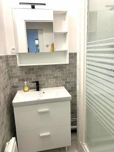 łazienka z białą umywalką i lustrem w obiekcie Appartement montagne w mieście Eaux-Bonnes +7 zdjęć