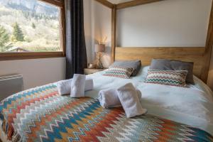 um quarto com uma cama grande com almofadas e uma janela em Les Eaux Cristallines de Bredannaz, unique vue lac 6p LLA Selections by Location lac Annecy em Doussard