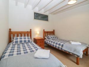 a bedroom with two beds and a table with a lamp at Blackberry Cottage in Kingsbridge