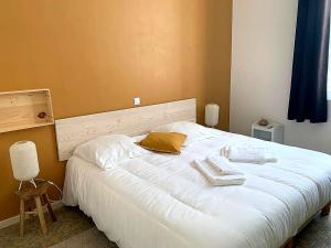 sypialnia z białym łóżkiem i 2 ręcznikami w obiekcie Appartement montagne w mieście Eaux-Bonnes