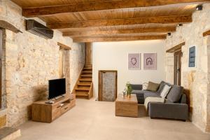 a living room with a couch and a tv at Antama Living, Luxe Stonehouse with Pool & BBQ in Rethymno Town