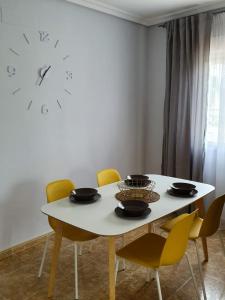 Playamarina 1 Reception في كابو رويج: طاولة طعام مع كراسي وساعة على الحائط