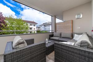 balcón con muebles de mimbre y ventana grande en Appartament Emma en Brunico
