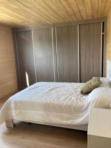 um quarto com uma grande cama branca e paredes de madeira em Apartamento Blanco em Mazaricos