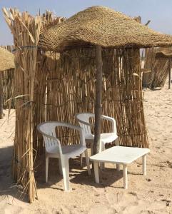 duas cadeiras e uma mesa em frente a uma cabana na praia em Renaissance em Bou Ficha