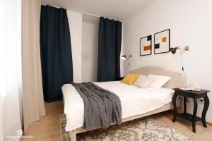 a bedroom with a white bed with blue curtains at Chic Concept Studio in Bucharest