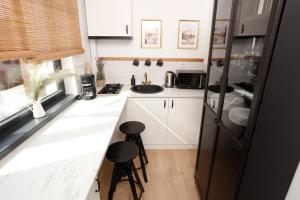 a small kitchen with white cabinets and black appliances at Chic Concept Studio in Bucharest