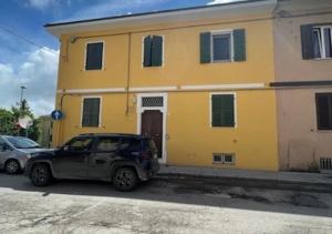 un coche aparcado frente a un edificio amarillo en Cleo Viola en Ancona