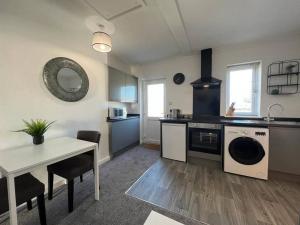 a kitchen with a table and a sink and a dishwasher at Flat 2 High Street Apartments, One Bed in Wellington