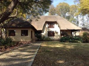Biały dom z dachem krytym strzechą w obiekcie Matalatala Wildlife Lodge w mieście Roodeplaat