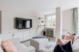 a living room with white furniture and a flat screen tv at Modern 2 bed, cliff top & parking, F6 in Southbourne