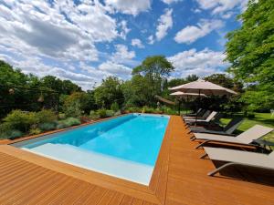 a swimming pool with lounge chairs and an umbrella at NAMASTE COTTAGE in Issigeac