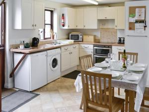 a kitchen with a table and a sink and a dishwasher at Florin Cottage in Lerryn