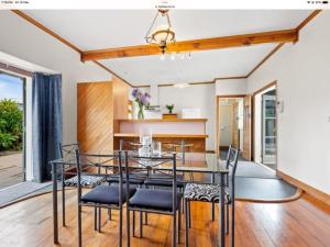 a dining room with a glass table and black chairs at Northern Holiday Cottage in Whangarei