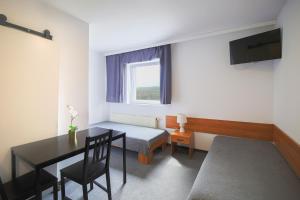 ein kleines Zimmer mit einem Tisch, einem Bett und einem Fenster in der Unterkunft Hotel pod Wieliczką in Gdów