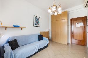een woonkamer met een blauwe bank en een kroonluchter bij Monolocale 12 in Pietra Ligure