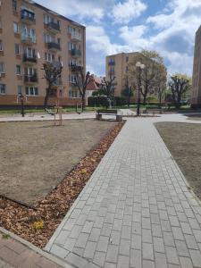 einen Gehweg in einem Park mit Bänken und Gebäuden in der Unterkunft Apartament centrum in Szczytno