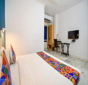 FabHotel Silverkey Kalighat في كولْكاتا: غرفة نوم مع سرير مع بطانية ملونة عليه