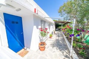 a blue door on a white building with potted plants at Little Villa - walk to the beach in Thessaloniki