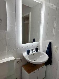 ein weißes Badezimmer mit einem Waschbecken und einem Spiegel in der Unterkunft FeWo Lindenallee in Nordhorn