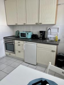 eine Küche mit weißen Schränken und einer weißen Mikrowelle in der Unterkunft FeWo Lindenallee in Nordhorn
