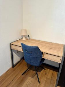 einen hölzernen Schreibtisch mit einem blauen Stuhl und einer Lampe in der Unterkunft FeWo Lindenallee in Nordhorn