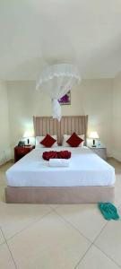 a bedroom with a large white bed with red pillows at Juba Landmark Hotel in Juba