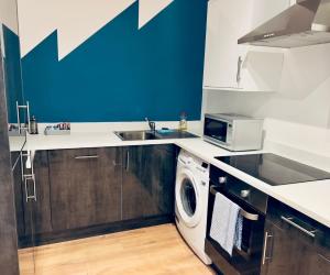 a kitchen with a sink and a washing machine at KVM - Lavish Style Apartment - Modern 2 Bedroom Apartment in Bayard FREE Parking - KVM Lavish Style Apartment by KVM Stays in Peterborough