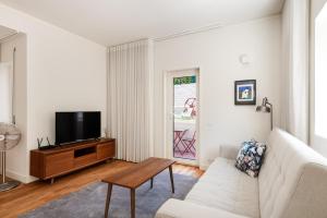 a living room with a white couch and a tv at Bombarda Homes in Porto
