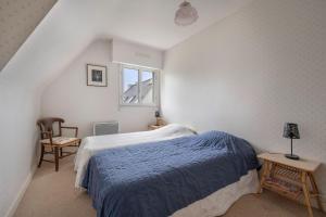 a bedroom with a bed with a blue blanket and a window at Incroyable emplacement à 110m de la plage in La Turballe