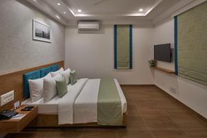 a bedroom with a bed and a tv on a wall at Regenta Inn 4th Block Koramangala Bangalore in Bangalore