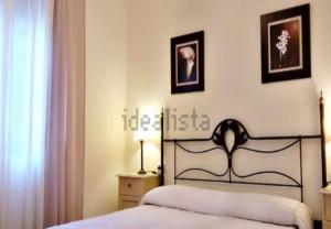 ein Schlafzimmer mit einem Bett und zwei Bildern an der Wand in der Unterkunft Villas de Islantilla in Isla Cristina