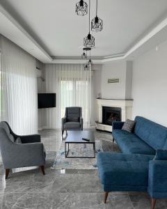 ein Wohnzimmer mit einem blauen Sofa und Stühlen in der Unterkunft Sapanca Çeşme Villaları in Feyziye